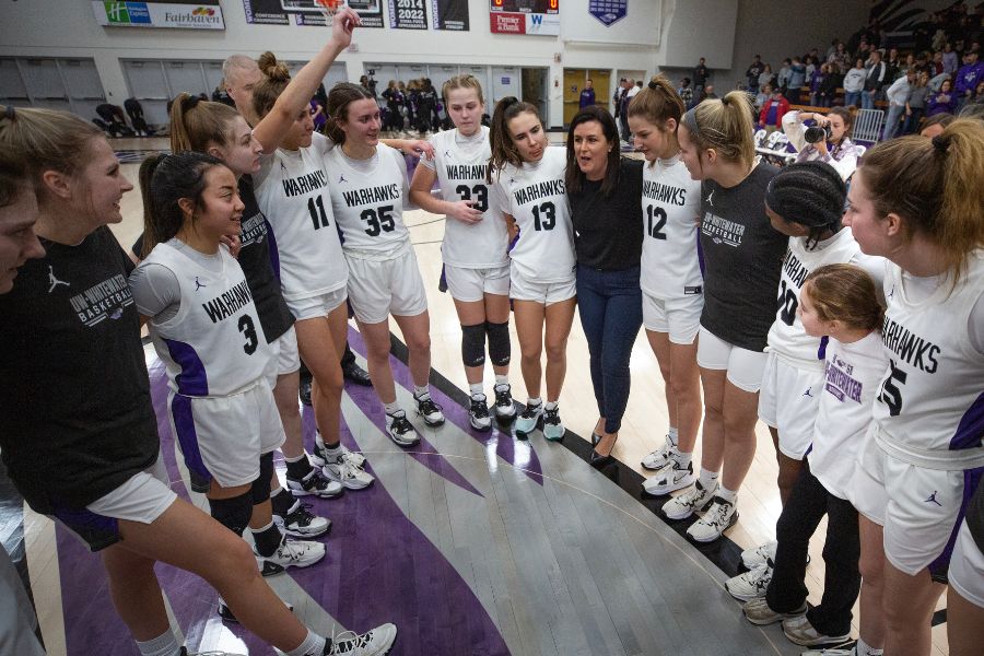 Basketball players hurdle in a circle with Coach Keri Carollo.