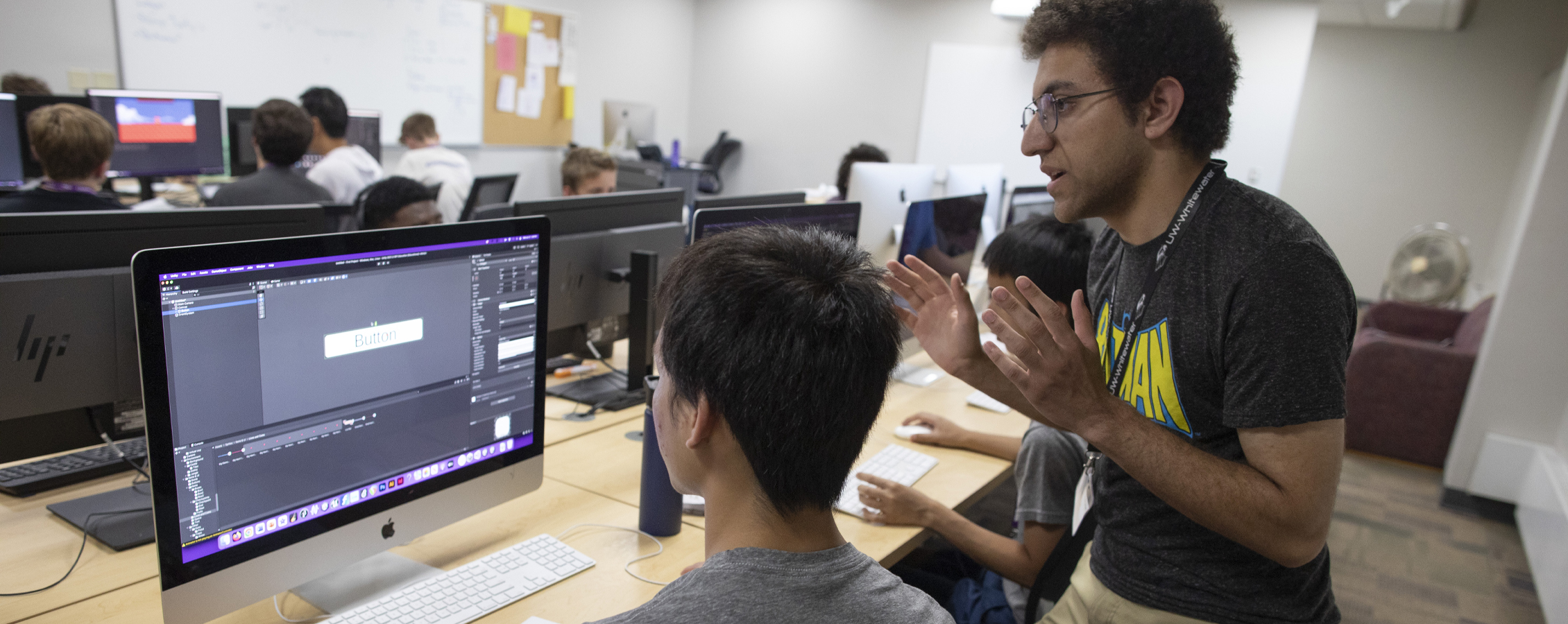 Students gather around computers to view their work.