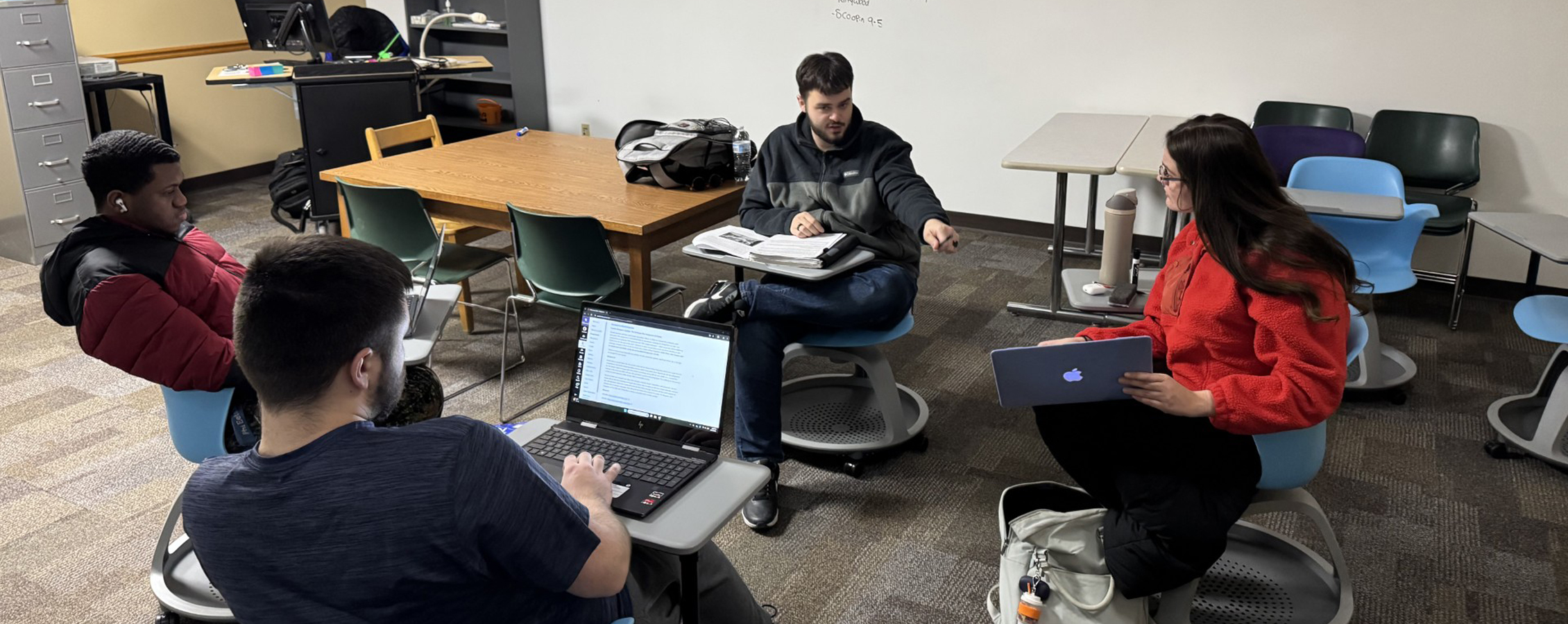 Students sit together in circle in a classroom.