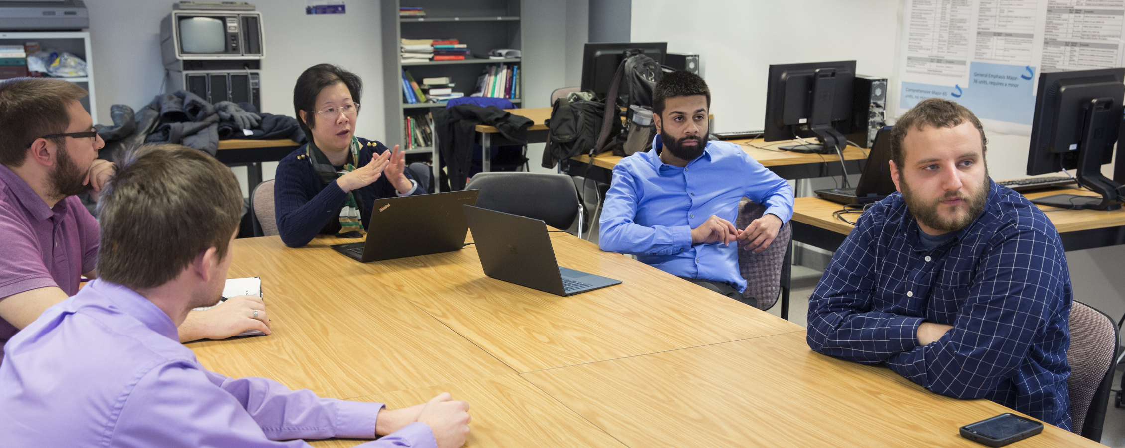 Students gather with a faculty member at a table.