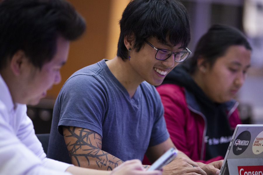 A student smiles while working on a computer.