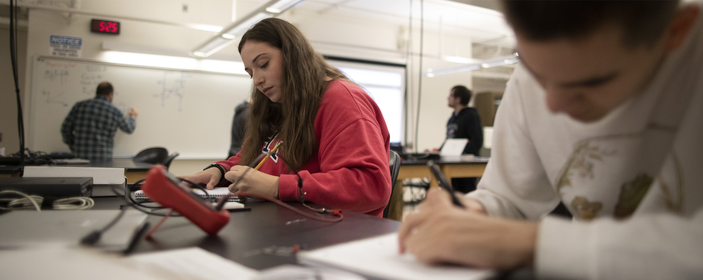 Students work together around a laptop.