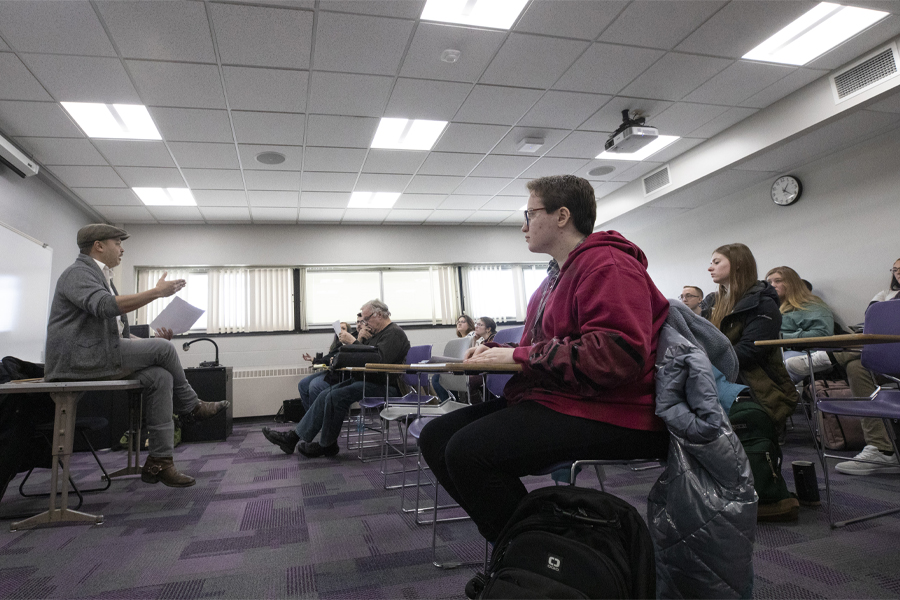 Nick Gulig sits on a table in front of class.