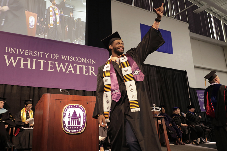 A student celebrates as they cross the stage during graduation.