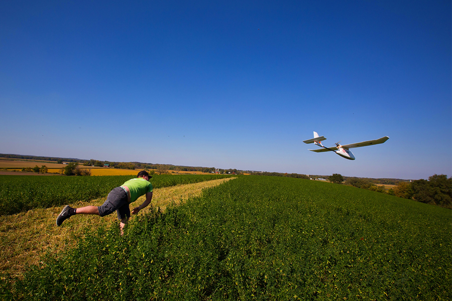 A student throws a mapping drone in a field.