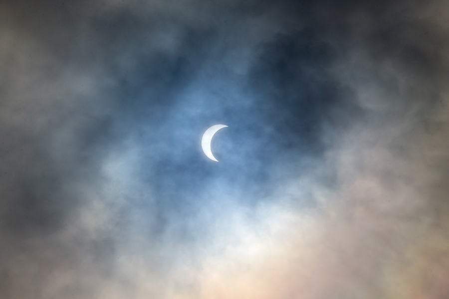 A solar eclipse surrounded by clouds.