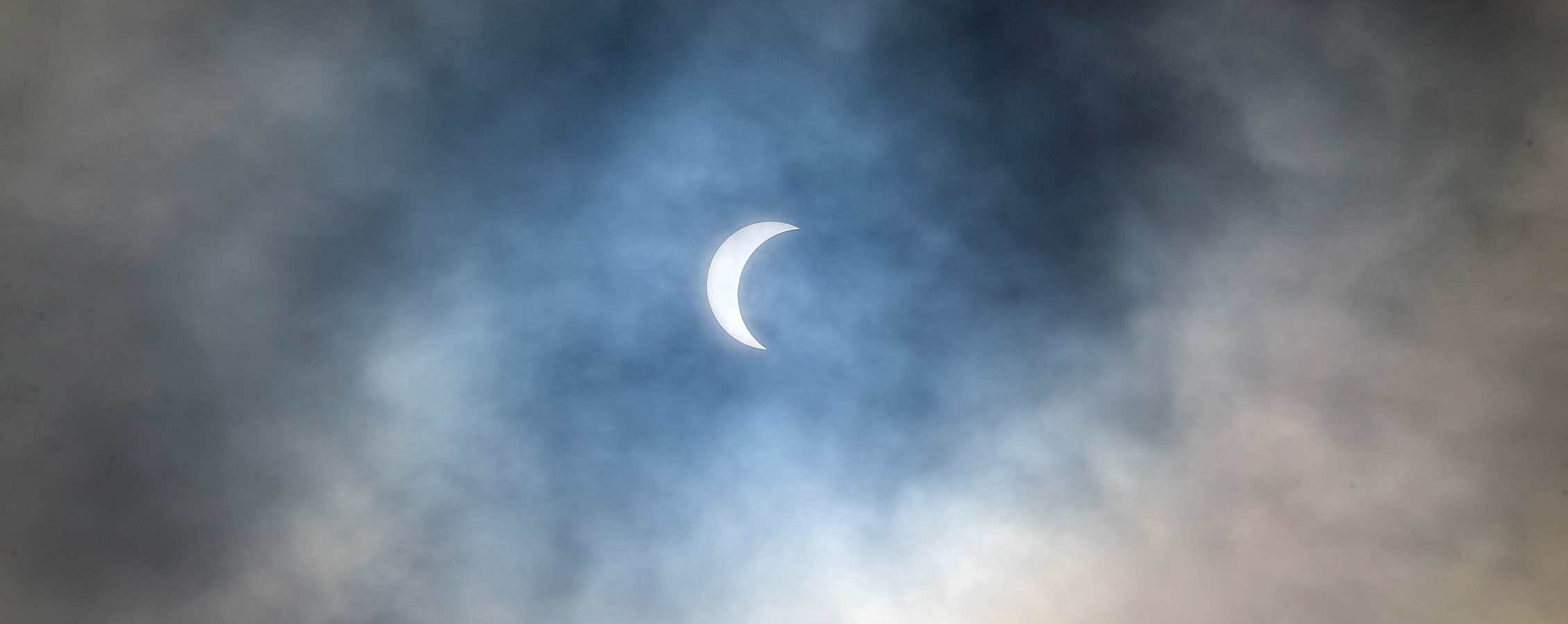 A solar eclipse surrounded by clouds.