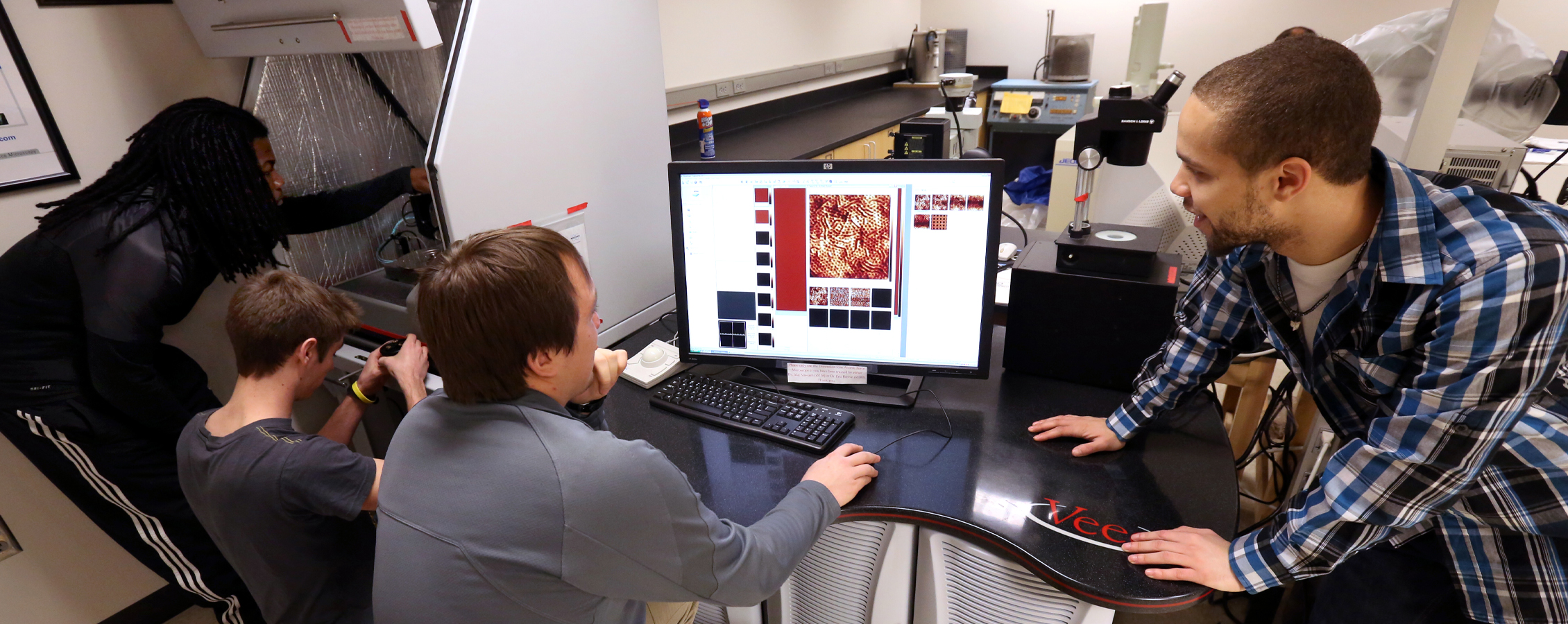 Students look at magnifications on a computer in the physics lab.