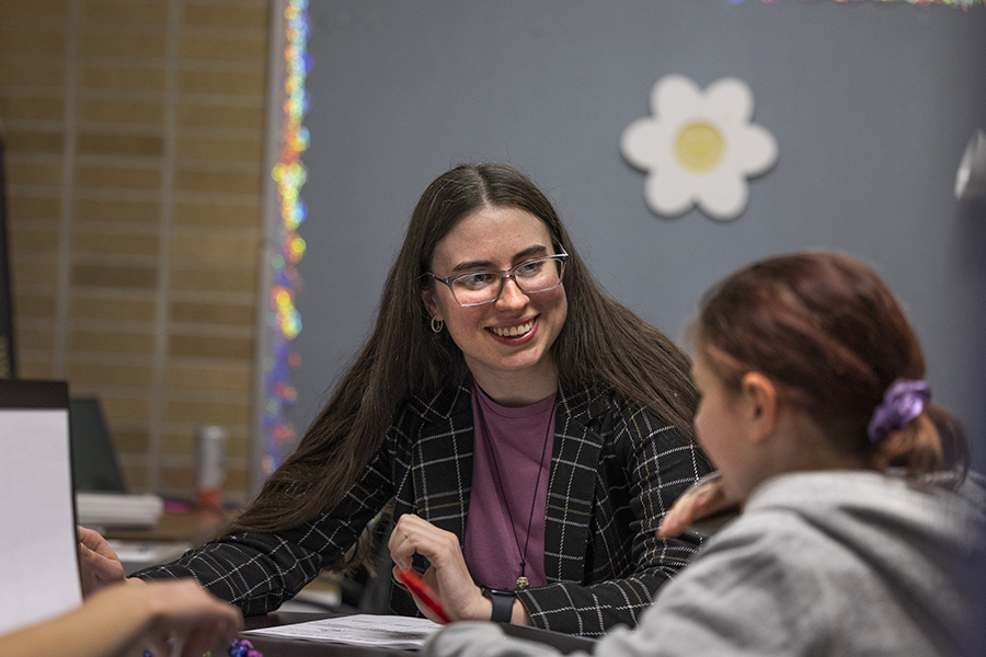 A school psychology student sits with a child in a classroom.