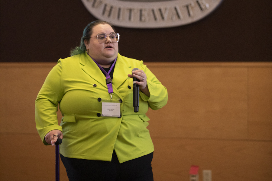 A person in a yellow coat speaks into a microphone.