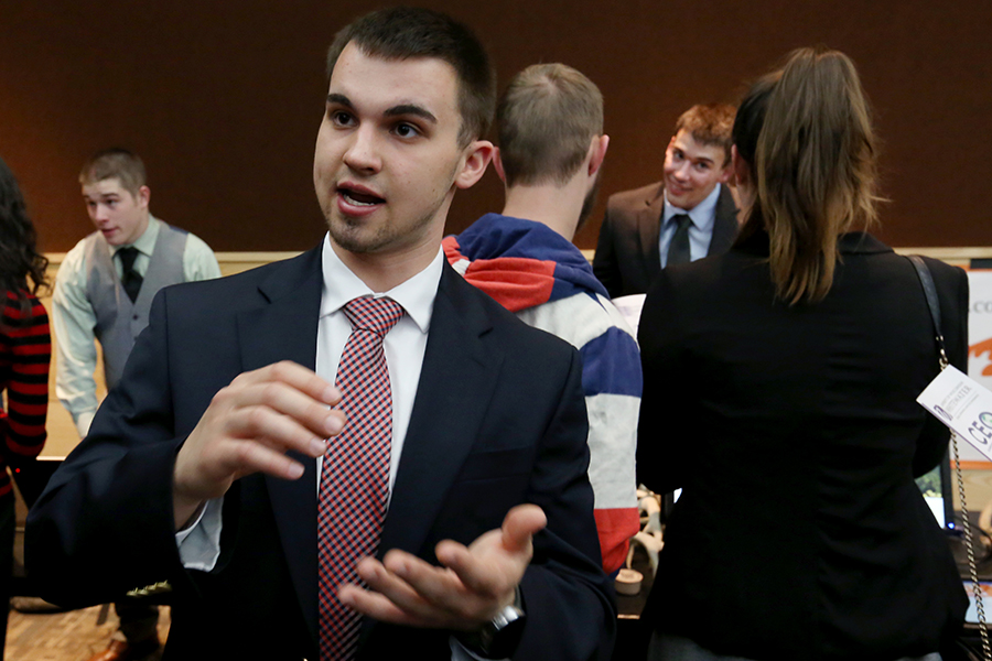 A student wearing a suit and tie gestures with his hands.