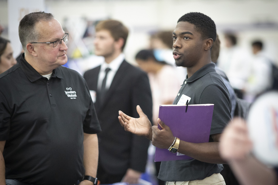 A business student speaks with a potential employer at a career fair.