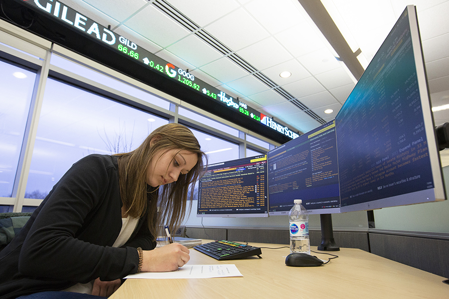 A student works at a desk in front of two computer monitors.