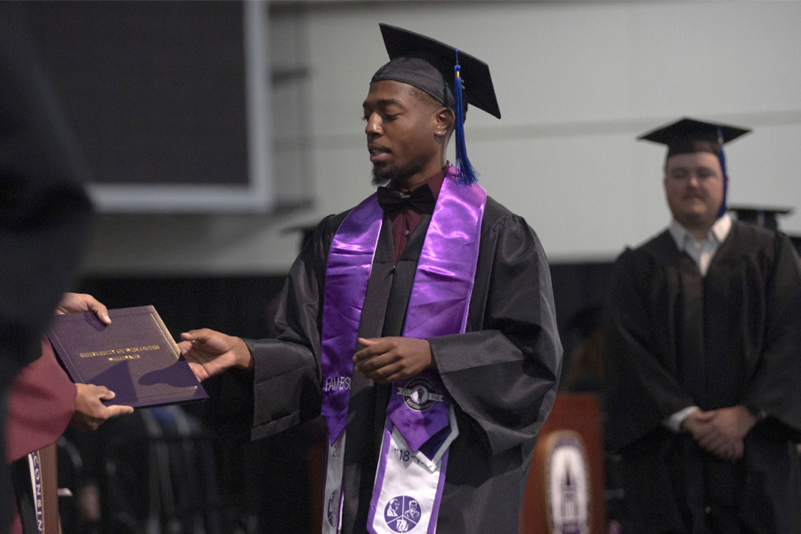 A student accepts their diploma as they walk across the stage at graduation.