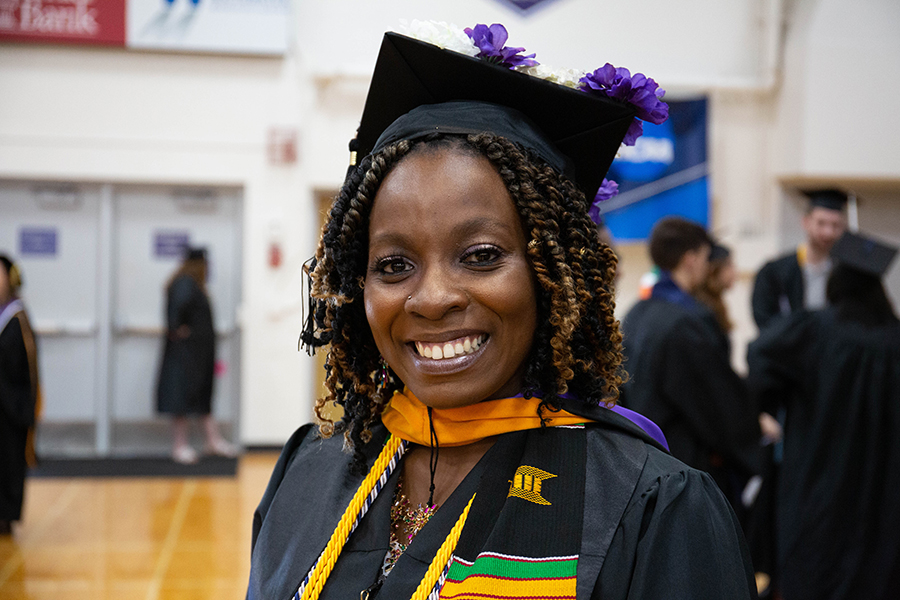 A graduate smiles while wearing their cap and gown.