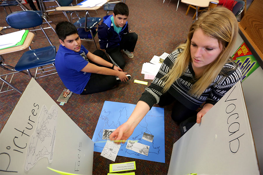 Middle school teacher teaches lesson to two students