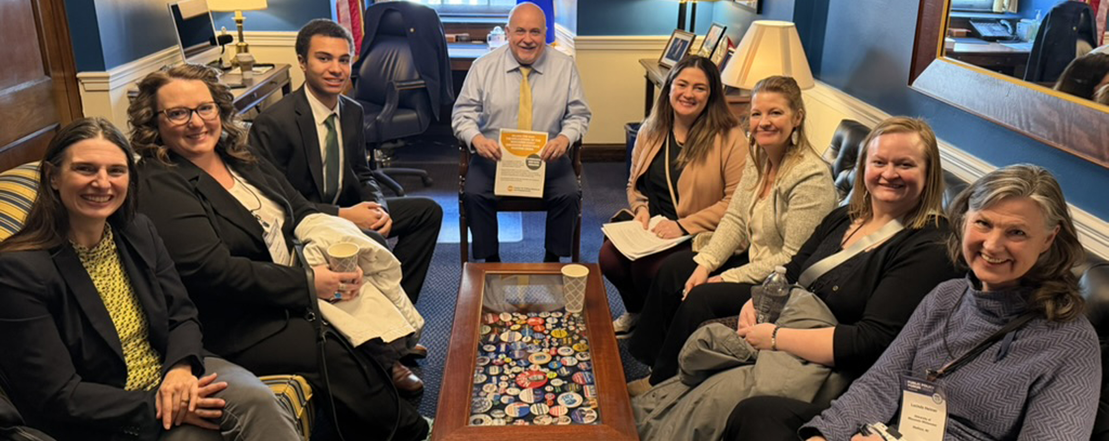 A group of people sit together around a coffee table.