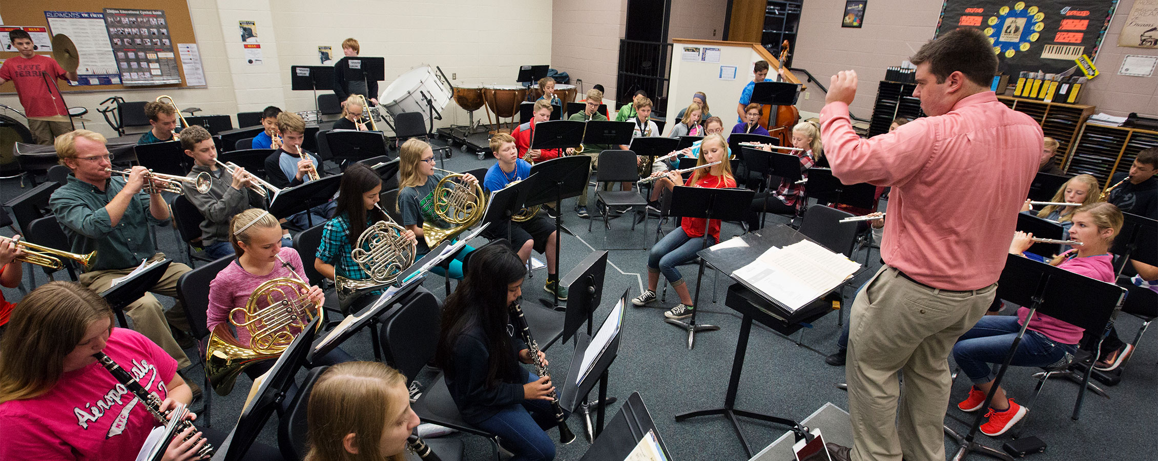 Elementary/Middle School music teacher conducting a group of students in rehearsal