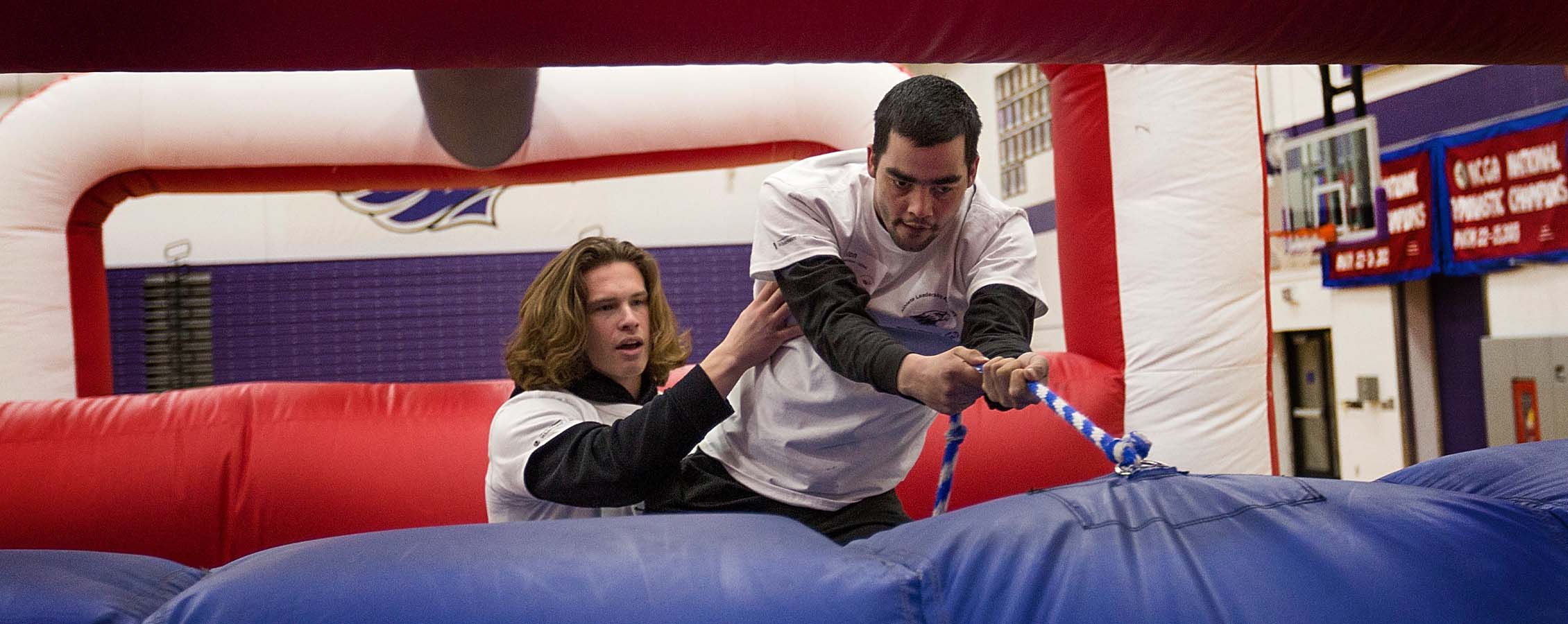 One person guides another person through air-filled gym equipment.