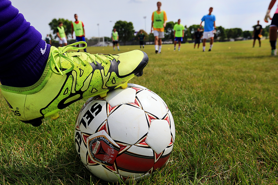 A yellow soccer cleat rests on a white and red soccer ball.