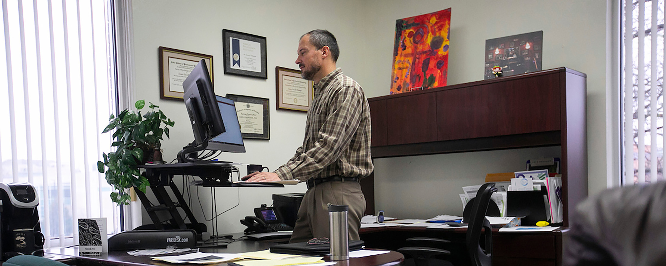 Man standing in front of standing desk working on computer.