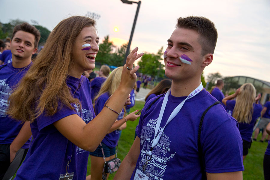 Students apply face paint during a welcome rally.