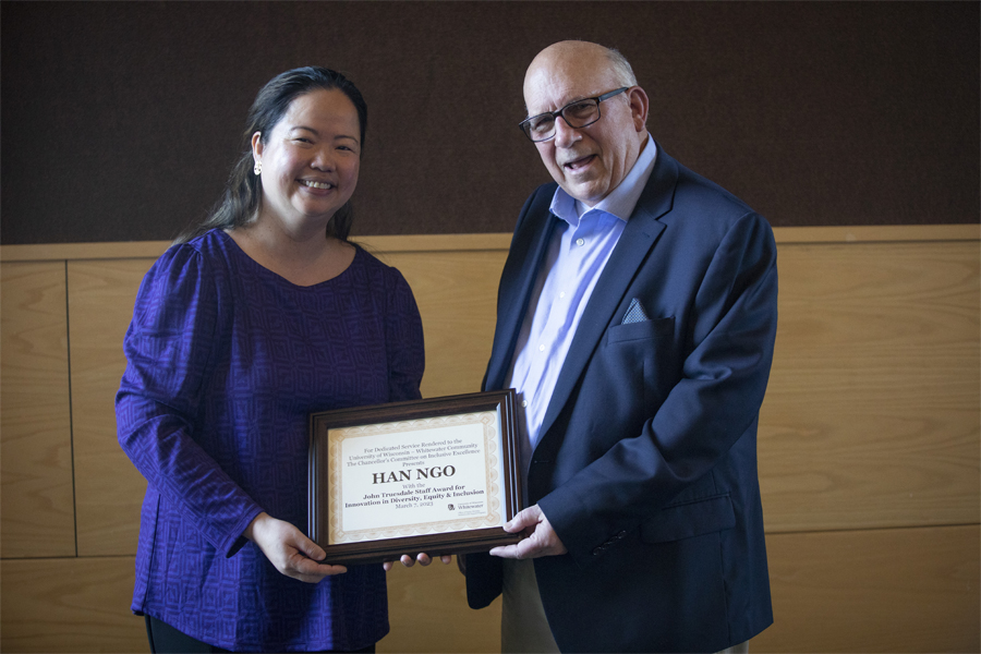 Two people stand together and hold a framed award.