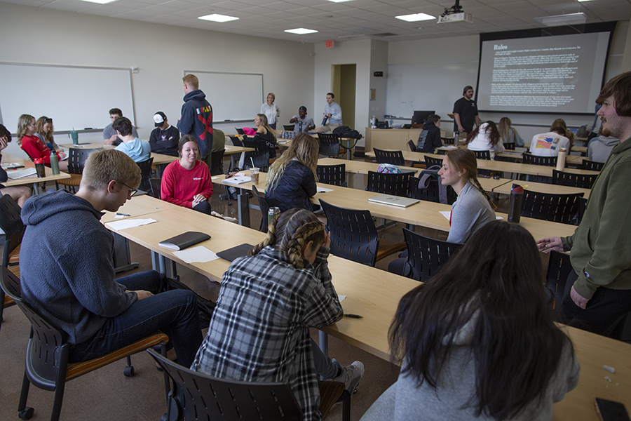 Students is at rowed tables in a classroom.