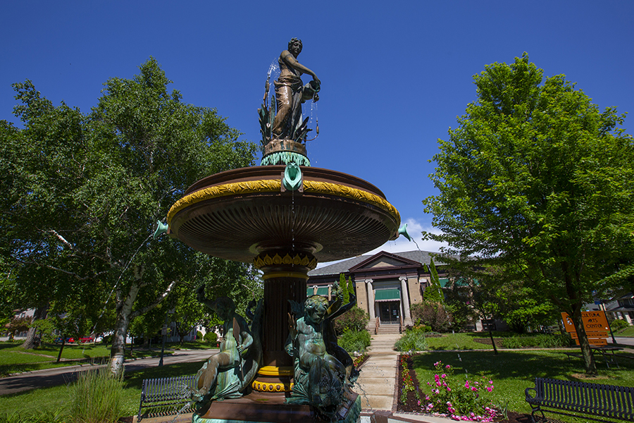 A two tier fountain in downtown Whitewater surrounded by trees.