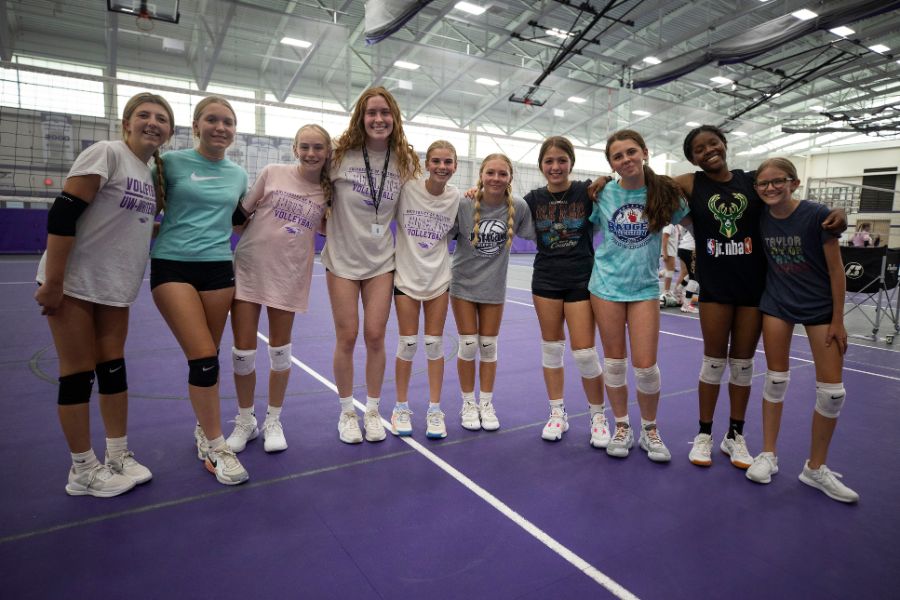 Volleyball players smile while posing for photo