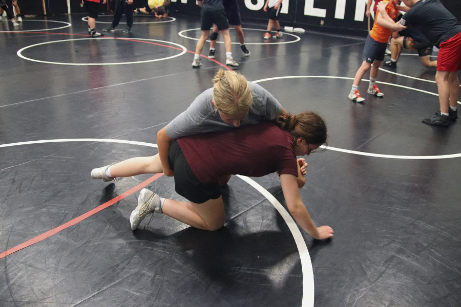 Students wrestling in a gym on a mat