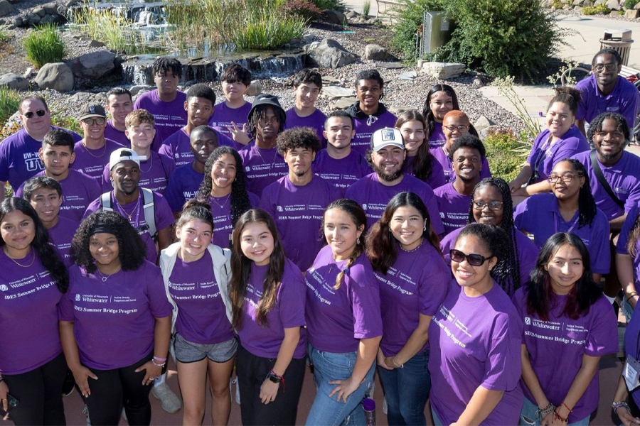 a large group of people wearing purple shirts pose for a photo outdoors.