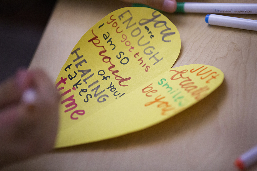 A heart is cut out of yellow paper with positive affirmations written on it in marker.