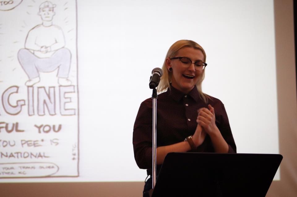 Student stands in front of a microphone to deliver a welcome to invited writer Ivan Coyote. 