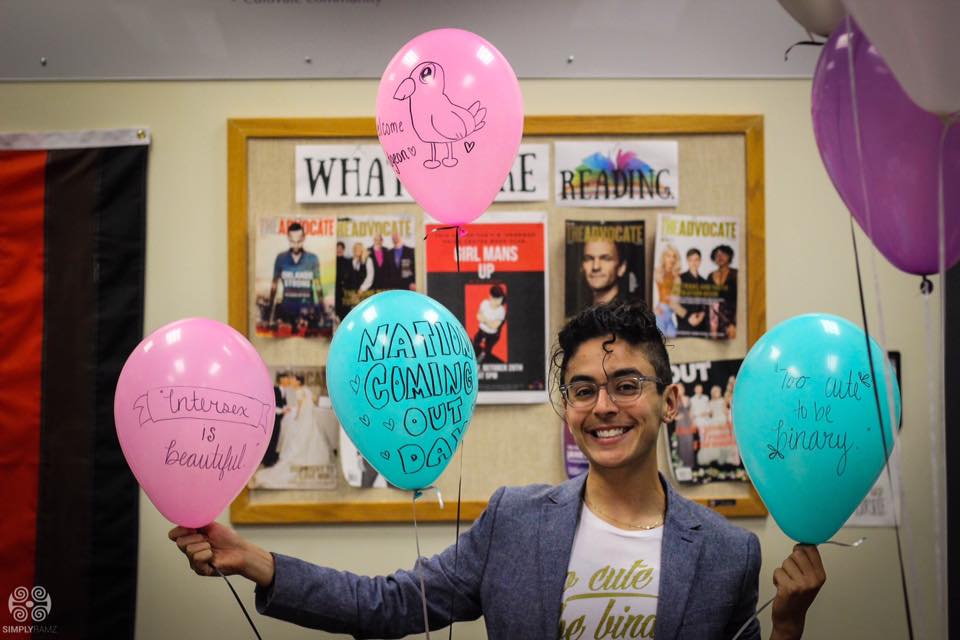 Pidgeon Pagonis holding pink and blue balloons in the Pride Center. 