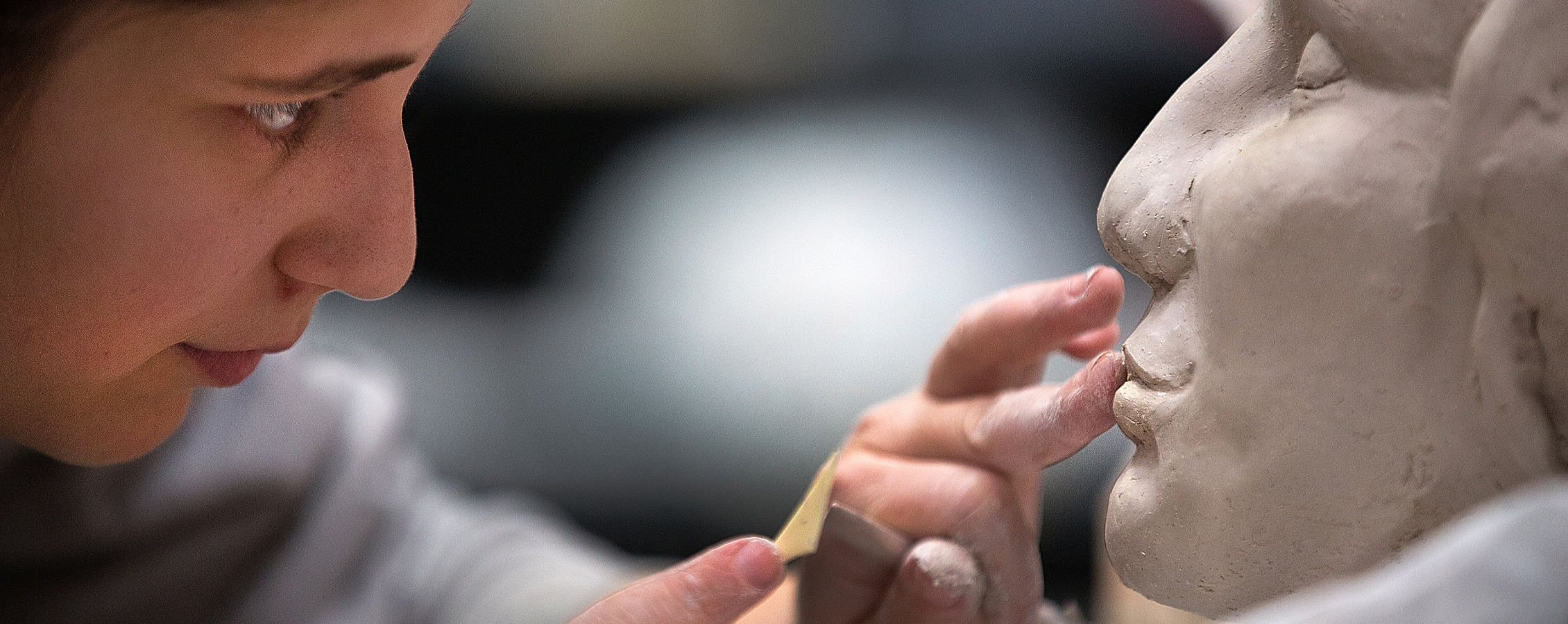 Person working on the face of a sculpture.