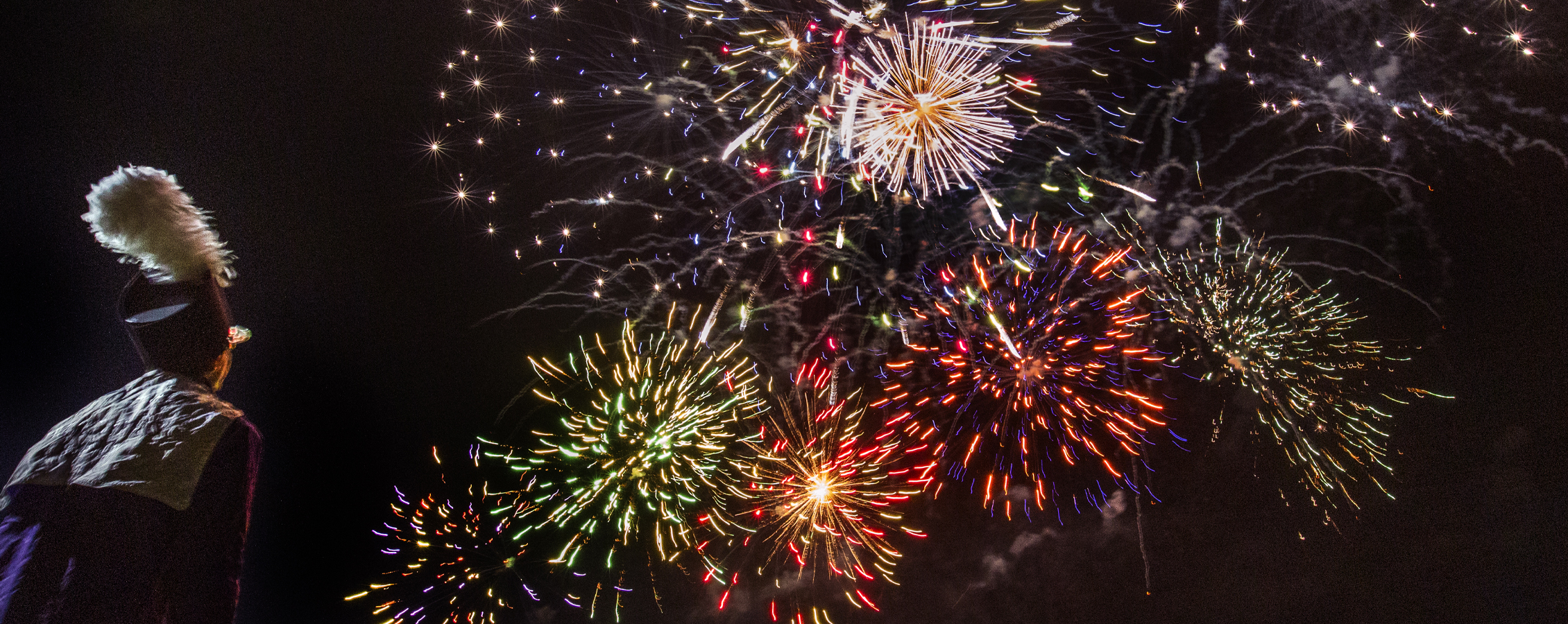 A Marching Band member watches fireworks.