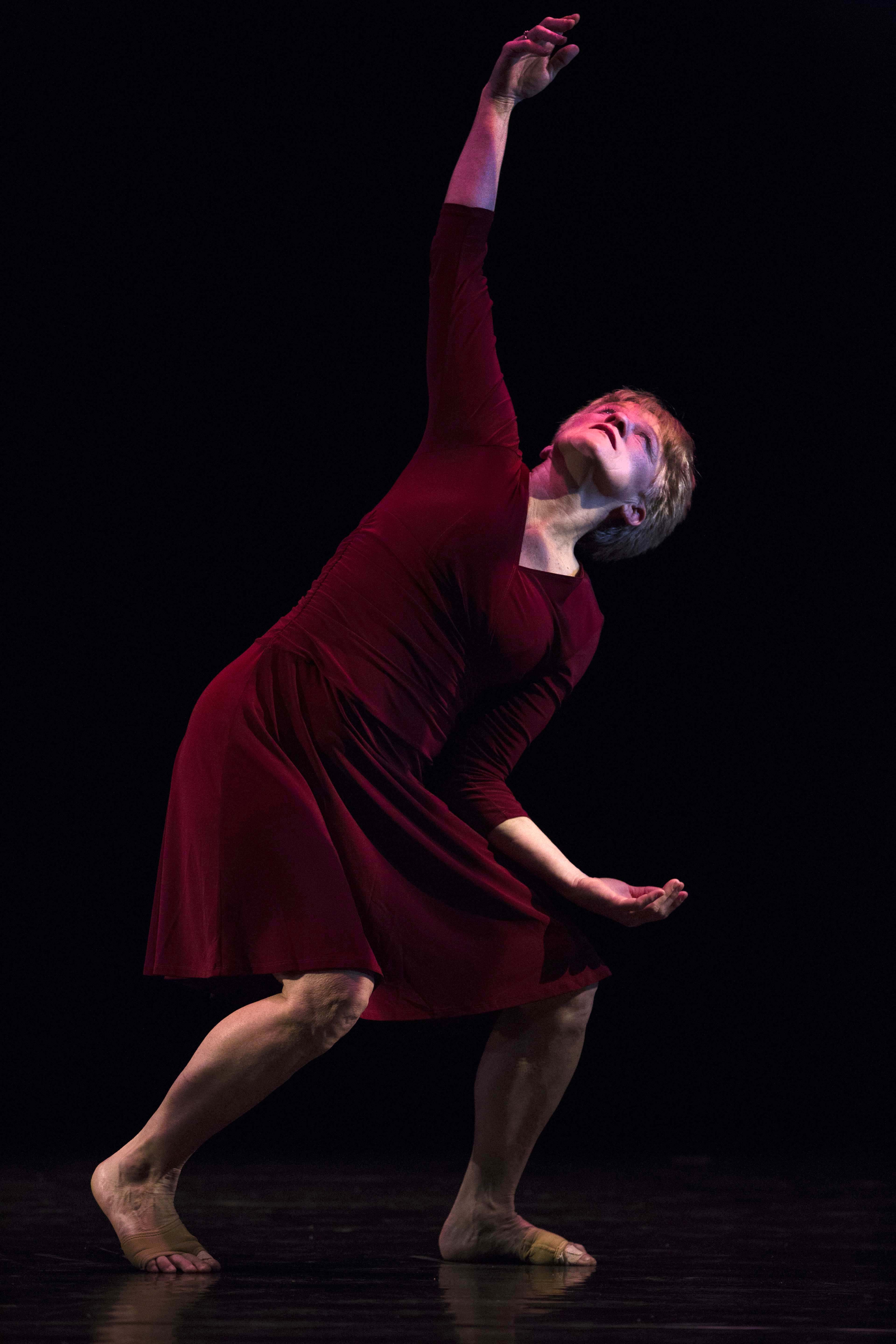 Dance performer wearing a red dress in dark lighting