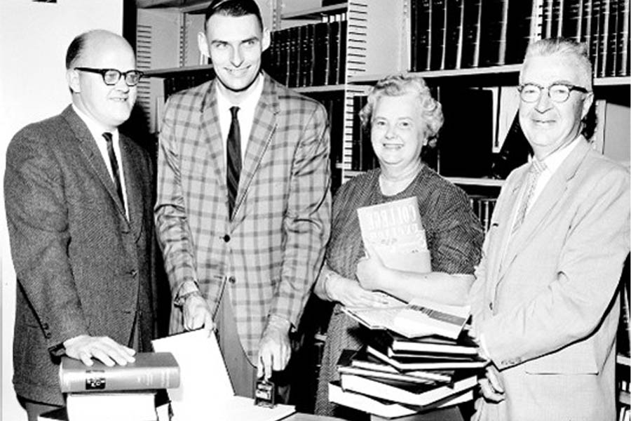 Helen Herbert standing among others in front of a bookshelf.