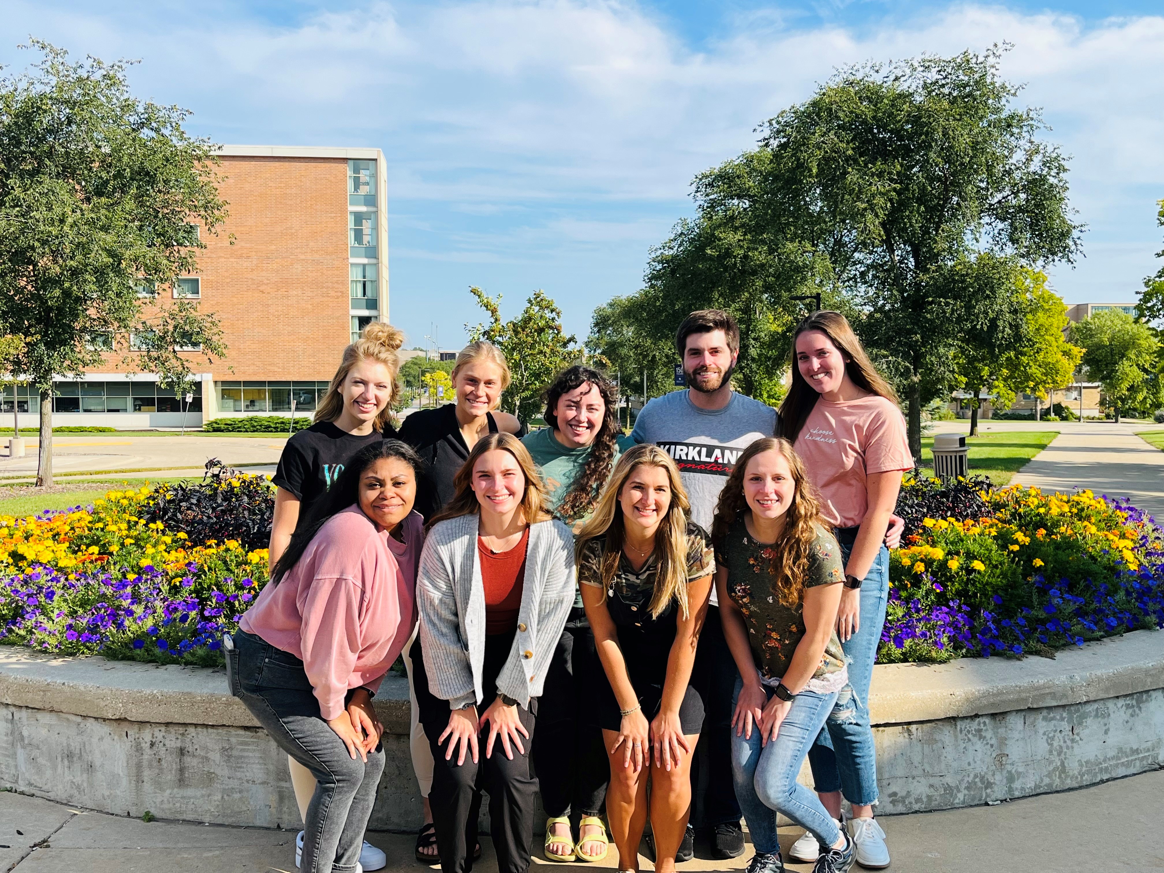 A small group of people stand together in two rows outdoors.