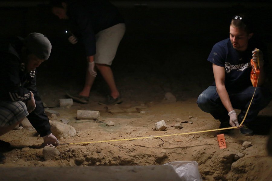 Two students use a tape measure at a mock crime scene.