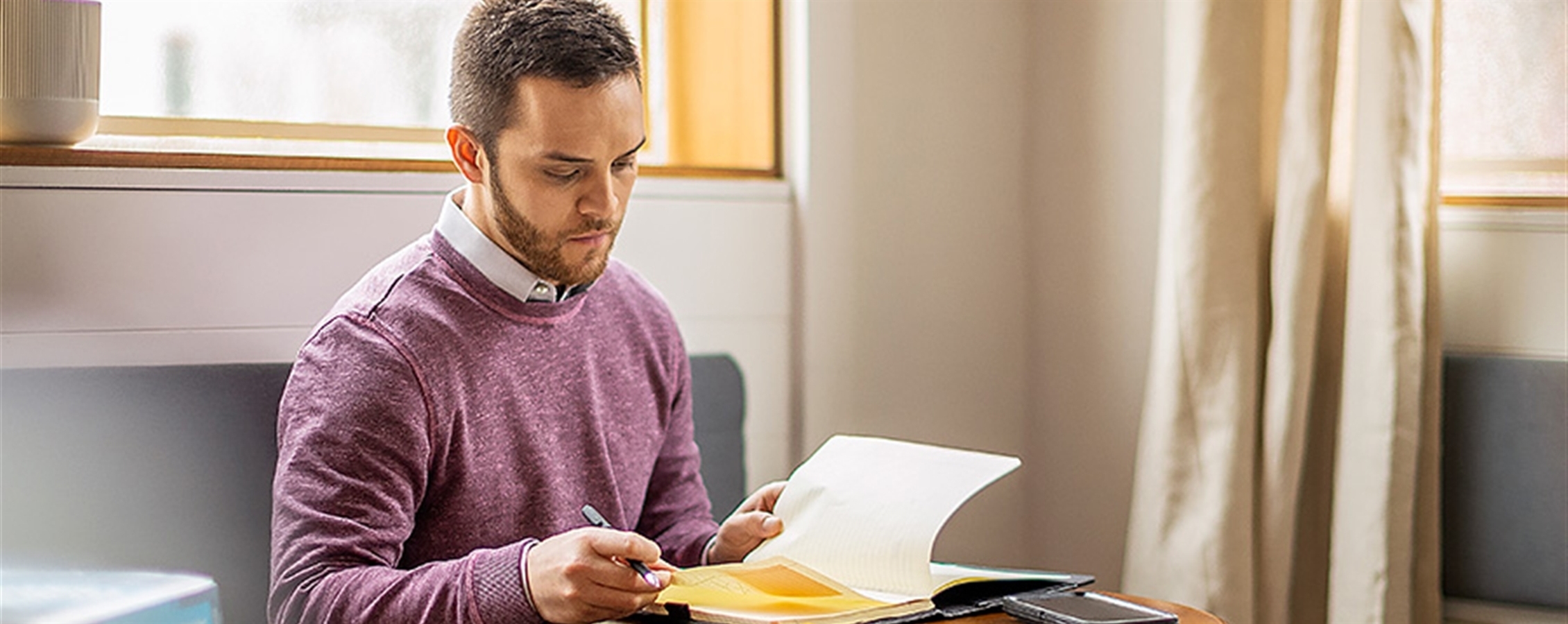 Man studying near cafe window with textbook