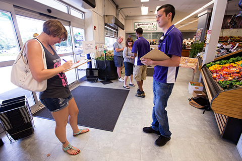 Student workers collect survey responses at an area grocery story for for a FERC research project.