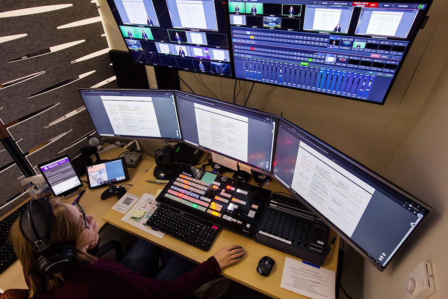 A student looking at three monitors doing work