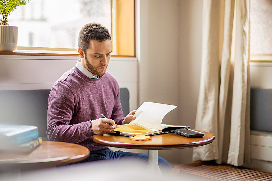 Man studying near cafe window with textbook