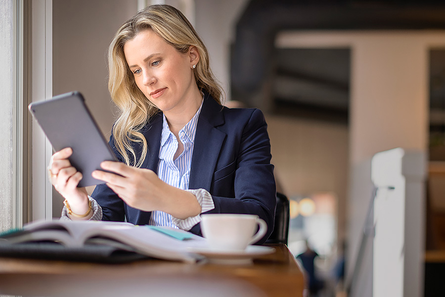 Woman studying with tablet by cafe window