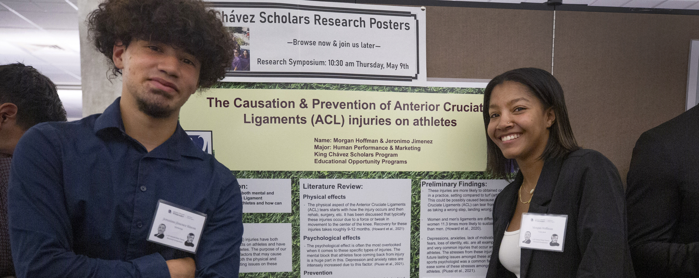 Two students stand on either side of a poster entitled The Causation & Prevention of ACL Injusries on Athletes. 