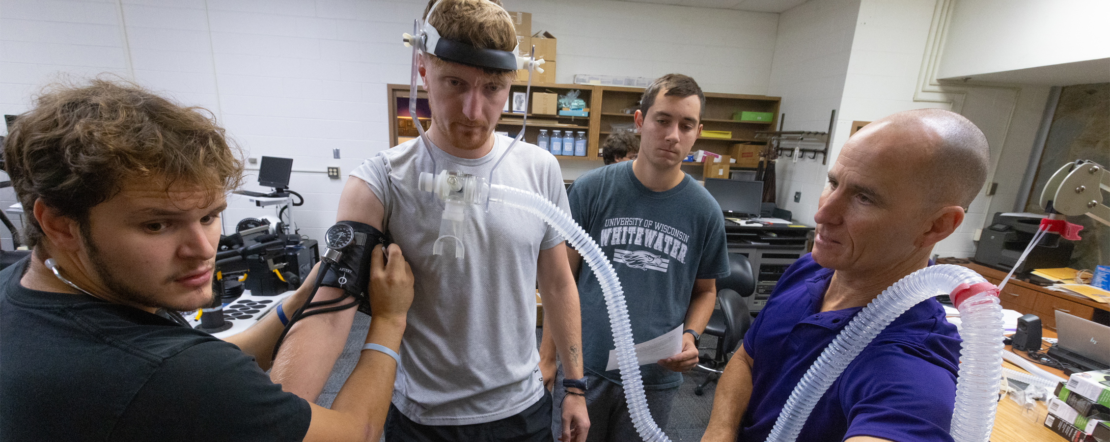 A faculty member stands with students during an exercise in a kinesiology class.