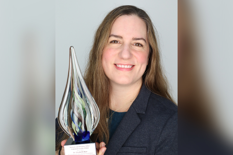 Elizabeth Blair holding a clear award in the shape of a teardrop.