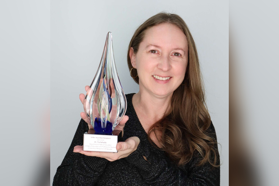 Tia Schultz holding a clear award in the shape of a teardrop.